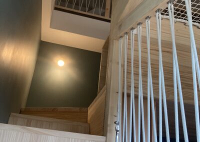 Vue du bas de l'escalier avec main courante en bois et cordage